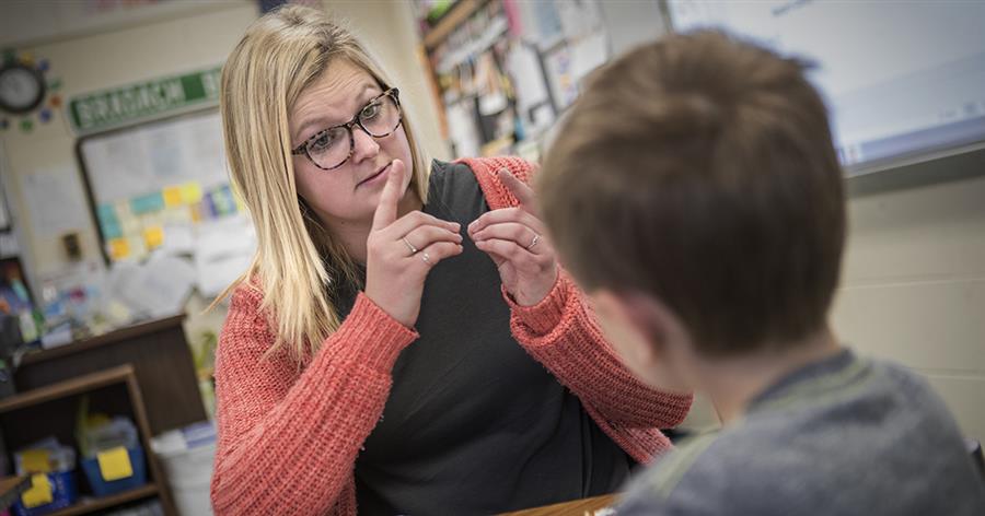 A teacher using American Sign Language to communicate with a student.